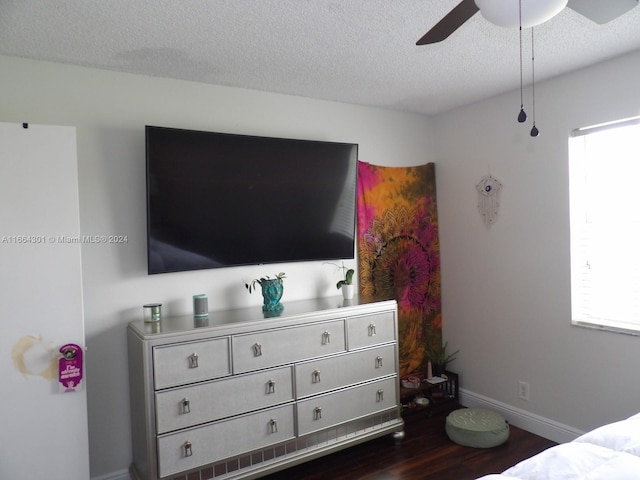 bedroom with ceiling fan, a textured ceiling, and dark hardwood / wood-style flooring