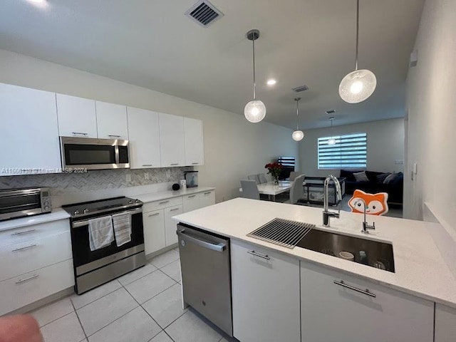 kitchen with hanging light fixtures, white cabinets, backsplash, stainless steel appliances, and sink