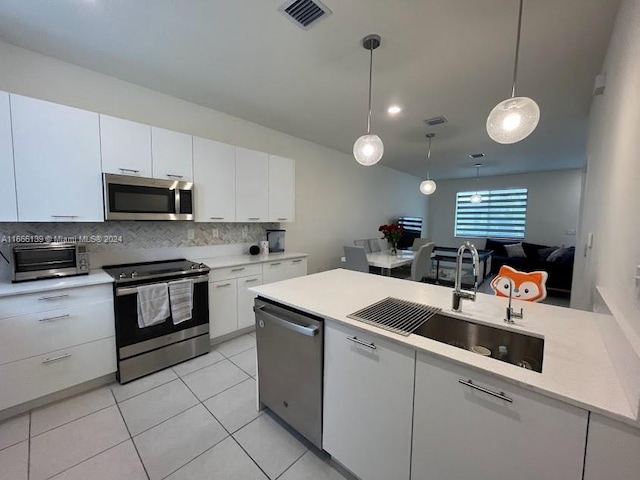 kitchen with appliances with stainless steel finishes, white cabinetry, sink, and decorative light fixtures