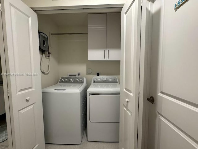 washroom featuring washer and clothes dryer, cabinets, and light tile patterned floors