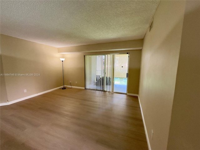 empty room featuring wood-type flooring and a textured ceiling