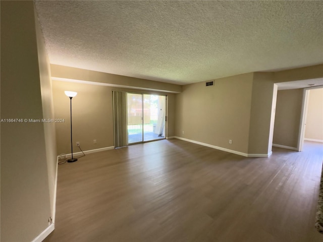 unfurnished room with a textured ceiling and hardwood / wood-style floors