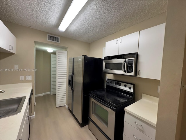 kitchen featuring light hardwood / wood-style floors, a textured ceiling, sink, white cabinetry, and appliances with stainless steel finishes