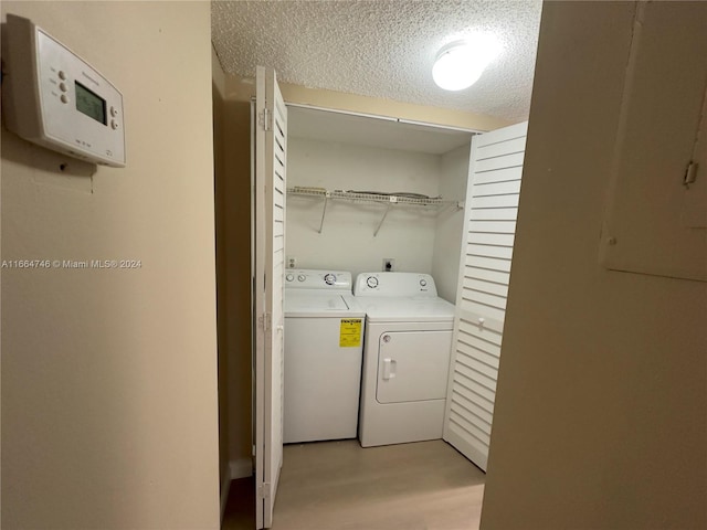 washroom featuring a textured ceiling, light wood-type flooring, and independent washer and dryer