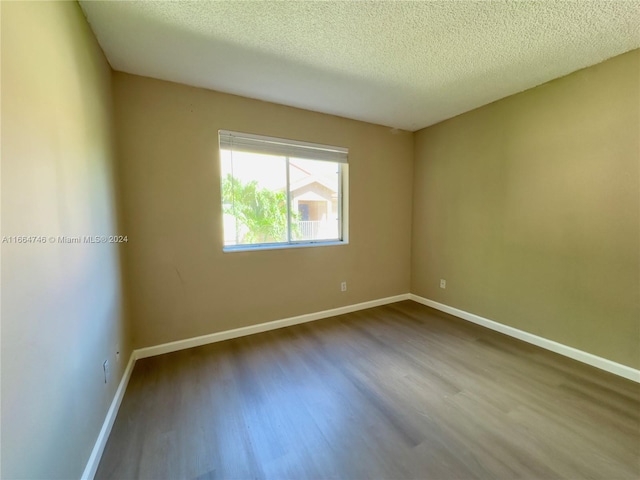 spare room with a textured ceiling and hardwood / wood-style floors