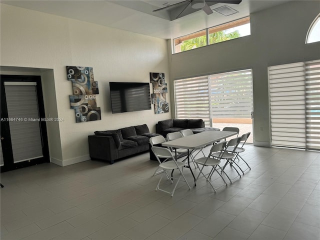 tiled dining space featuring a towering ceiling and ceiling fan