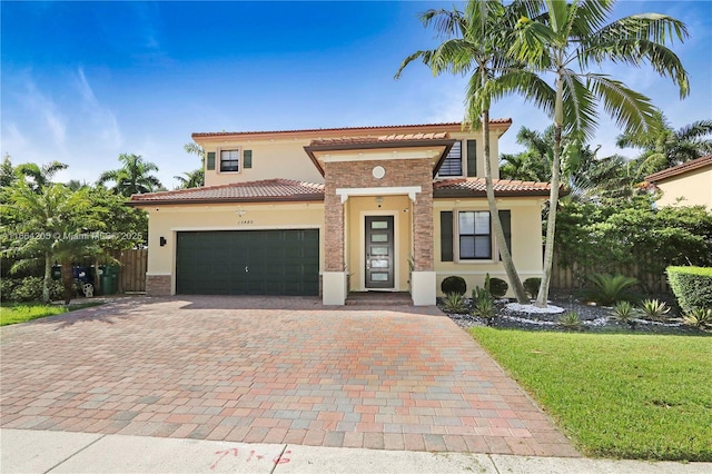 mediterranean / spanish-style house featuring fence, a tiled roof, stucco siding, decorative driveway, and an attached garage