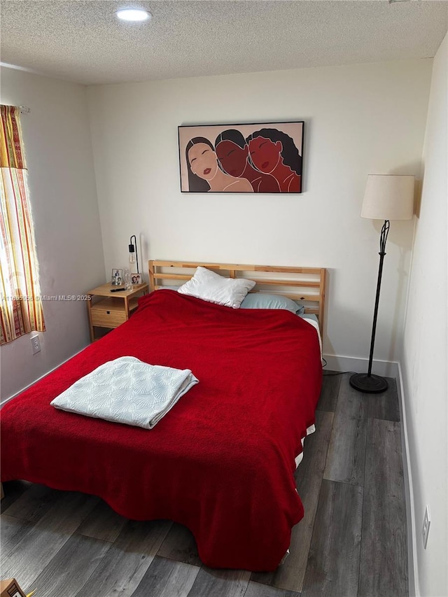 bedroom featuring a textured ceiling and dark hardwood / wood-style flooring