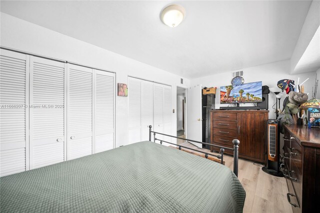 bedroom featuring multiple closets and light wood-type flooring