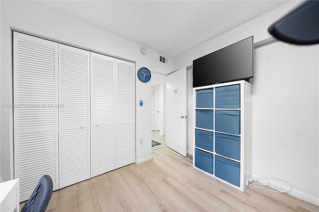 unfurnished bedroom with light wood finished floors, visible vents, and a closet