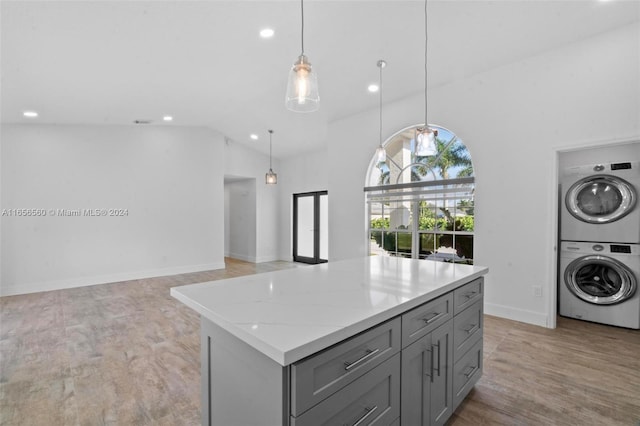 kitchen featuring light wood-type flooring, hanging light fixtures, stacked washing maching and dryer, and gray cabinets