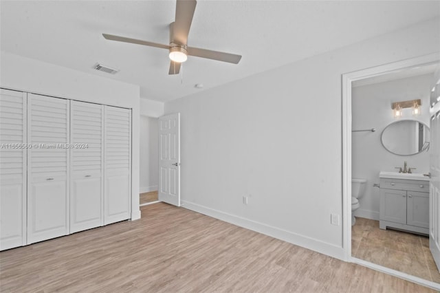 unfurnished bedroom with light hardwood / wood-style floors, ceiling fan, ensuite bathroom, and a closet