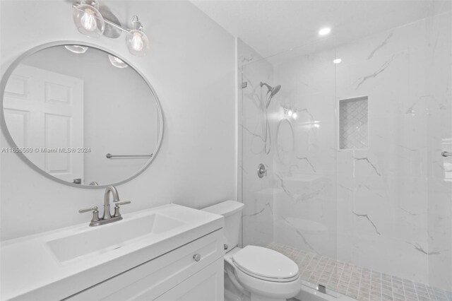 bathroom with tiled shower, vanity, and toilet