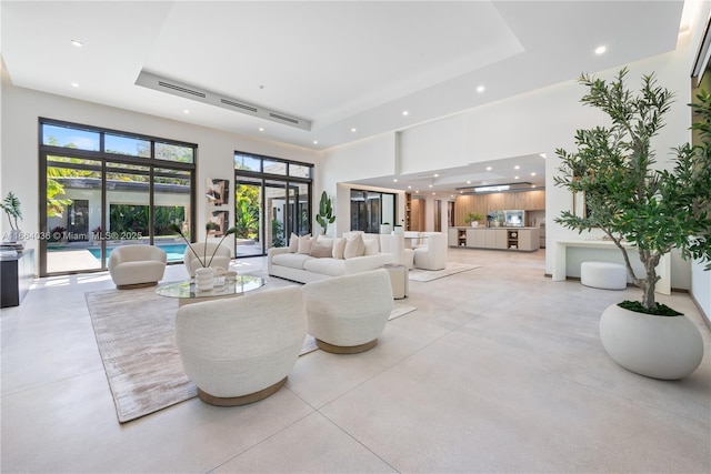 living room featuring a tray ceiling, a towering ceiling, and french doors