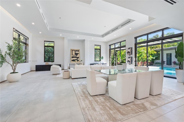 dining room with a wealth of natural light, a raised ceiling, and a high ceiling