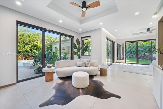 living room featuring ceiling fan and a tray ceiling