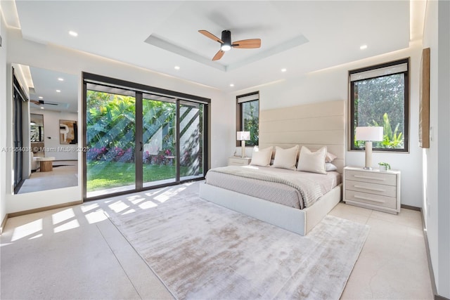 bedroom featuring ceiling fan, a tray ceiling, access to exterior, and multiple windows