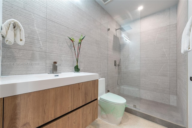 bathroom featuring tiled shower, vanity, toilet, and tile walls