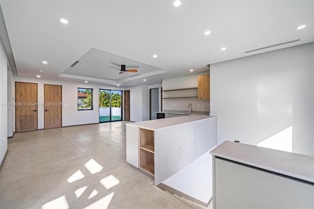 kitchen featuring sink, a raised ceiling, and ceiling fan