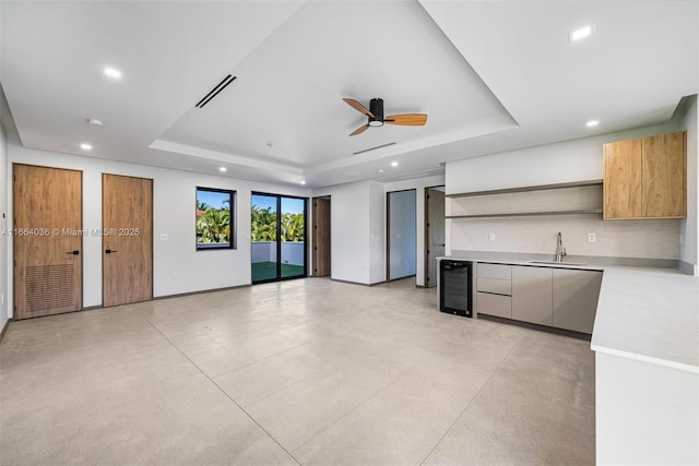 kitchen featuring wine cooler, backsplash, sink, and a raised ceiling