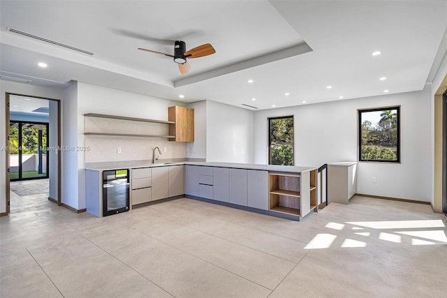 kitchen with wine cooler, a tray ceiling, sink, and tasteful backsplash