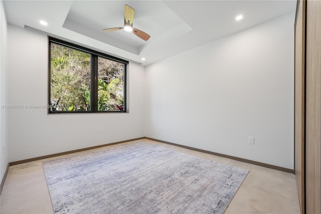 unfurnished room featuring a raised ceiling and ceiling fan