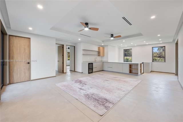 unfurnished living room with ceiling fan and a tray ceiling