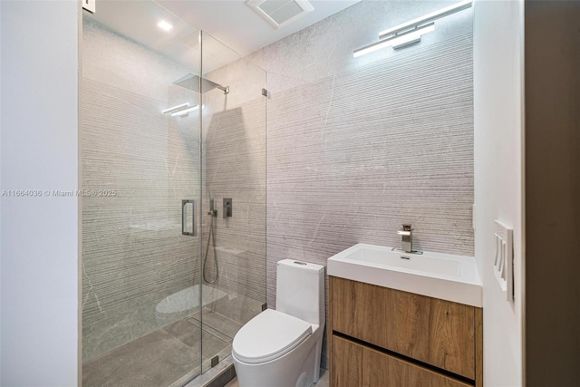 bathroom featuring vanity, toilet, a shower with door, and tile walls