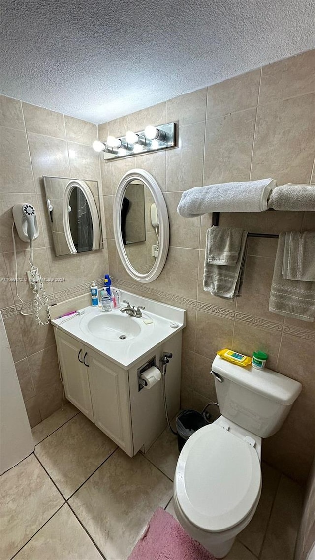 bathroom featuring tile walls, tile patterned flooring, a textured ceiling, vanity, and toilet