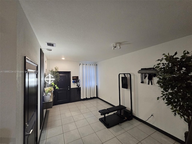 workout area with light tile patterned floors and a textured ceiling