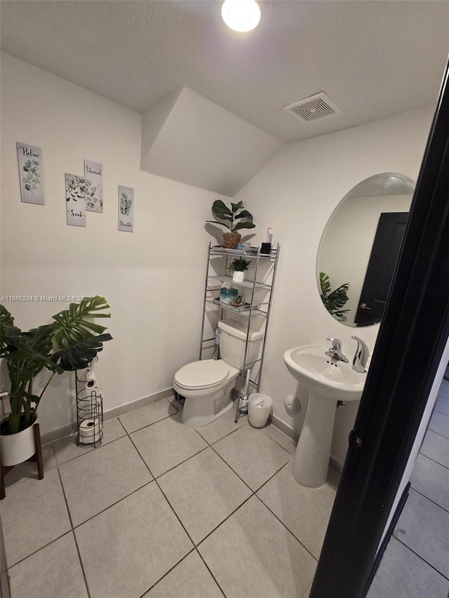 bathroom featuring tile patterned floors, toilet, and lofted ceiling