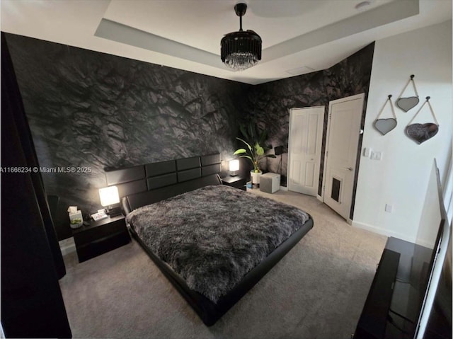 bedroom with light colored carpet and a tray ceiling