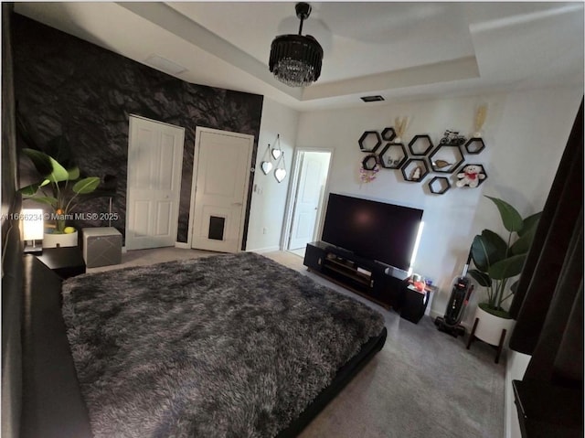 bedroom featuring carpet, a tray ceiling, and a notable chandelier