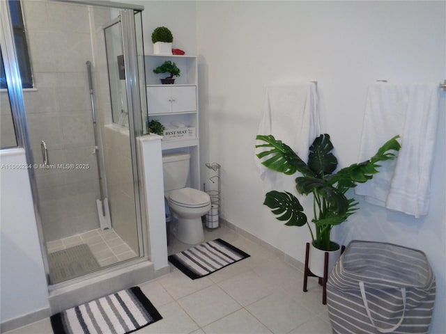 bathroom featuring toilet, tile patterned floors, and a shower with door