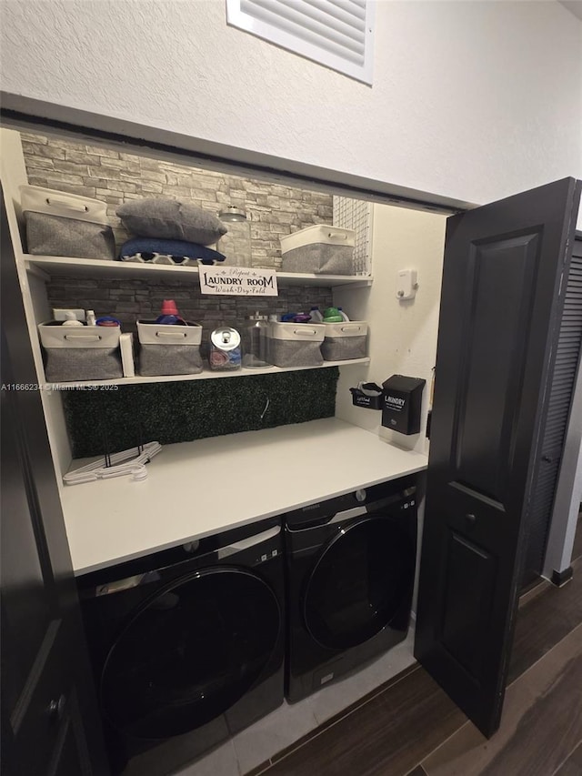 clothes washing area with washing machine and clothes dryer and dark hardwood / wood-style flooring