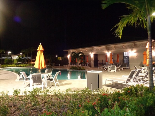 pool at twilight with a patio area