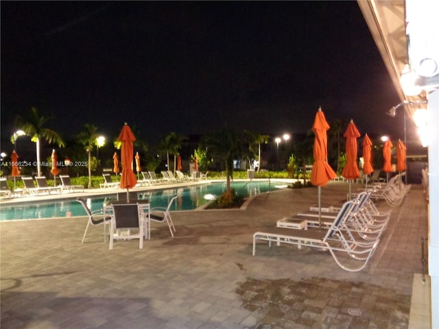 pool at twilight featuring a patio area