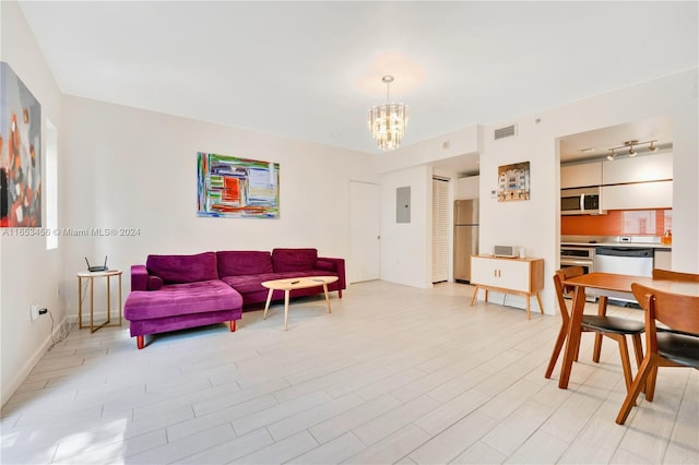 living room featuring a notable chandelier, electric panel, and light hardwood / wood-style floors