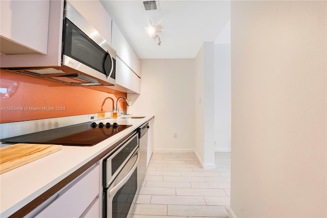 kitchen with stainless steel appliances, sink, and white cabinetry