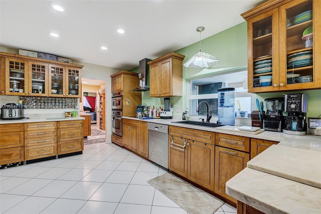 kitchen featuring light tile patterned floors, stainless steel appliances, decorative light fixtures, sink, and wall chimney range hood