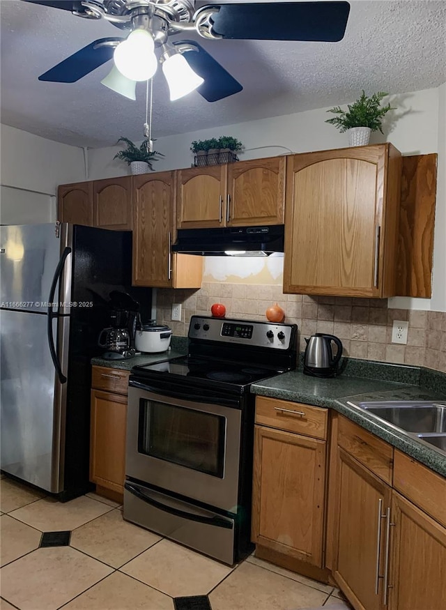 kitchen featuring decorative backsplash, light tile patterned floors, ceiling fan, stainless steel appliances, and a textured ceiling