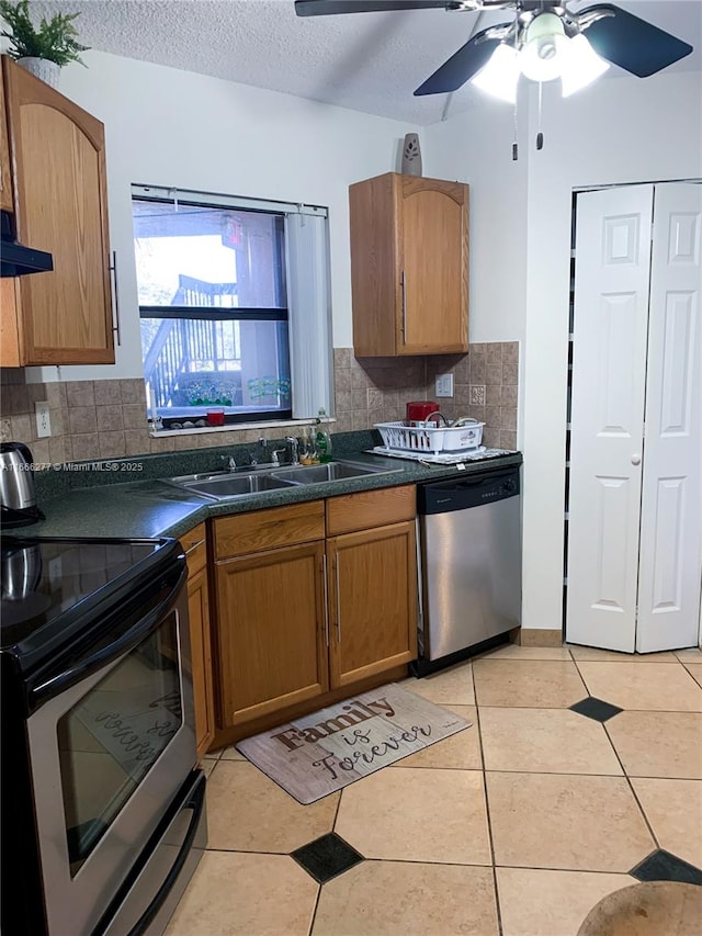 kitchen featuring appliances with stainless steel finishes, sink, decorative backsplash, light tile patterned floors, and a textured ceiling