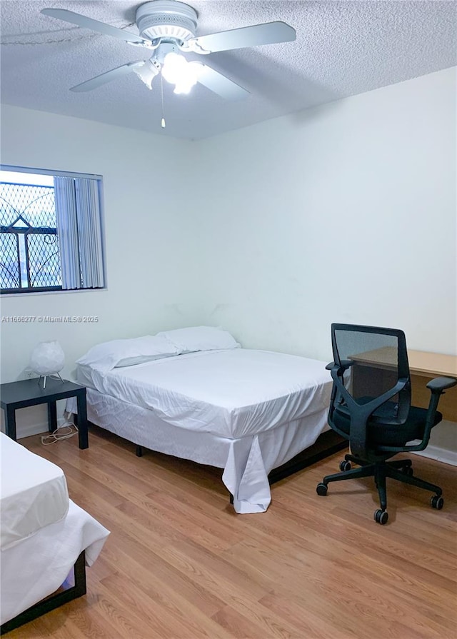 bedroom with ceiling fan, a textured ceiling, and light wood-type flooring