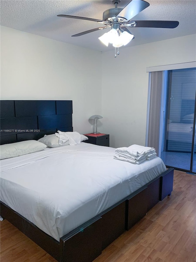 bedroom with ceiling fan, hardwood / wood-style flooring, and a textured ceiling