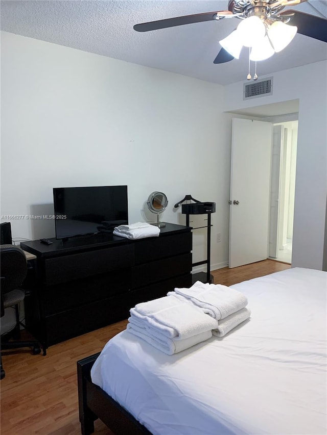 bedroom with hardwood / wood-style floors, a textured ceiling, and ceiling fan