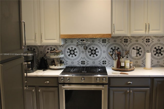 kitchen with light stone counters, stainless steel range, and white cabinets