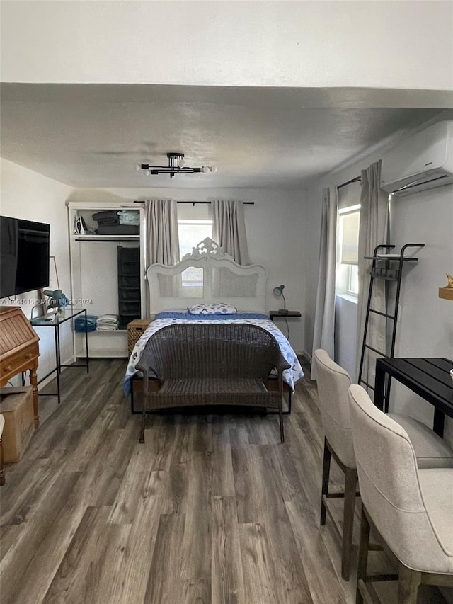 bedroom with dark hardwood / wood-style flooring and an AC wall unit