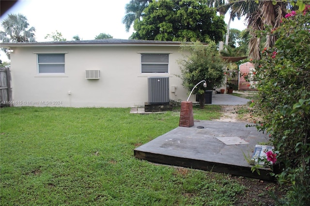 rear view of house with a lawn, a patio area, and a wall unit AC