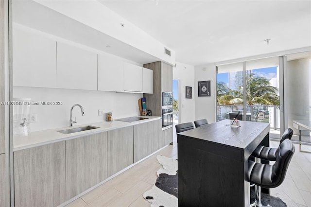 kitchen featuring a breakfast bar, sink, white cabinetry, a kitchen island, and appliances with stainless steel finishes