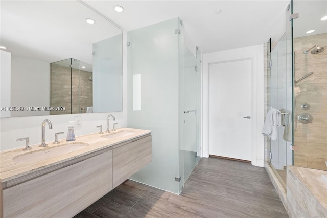 bathroom featuring a shower with shower door, hardwood / wood-style flooring, and vanity